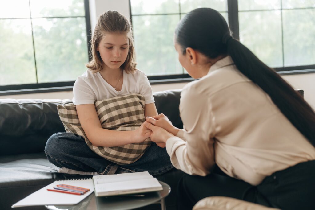 teen girl reluctant to talk her therapist while the therapist tries to comfort her