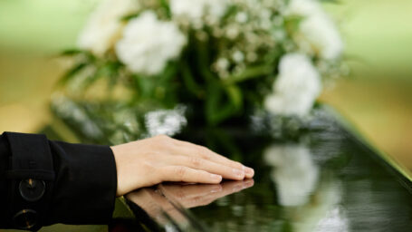 Woman laying a hand on a coffin