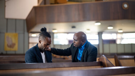 Pastor praying for a member of his church