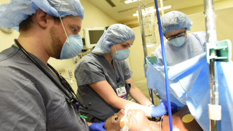 Medical staff practice CPR on mannequin