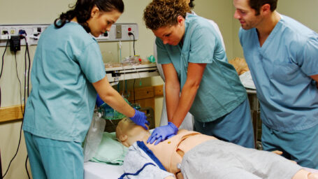Medical staff practice CPR on mannequin