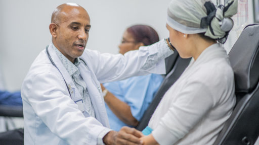 Image of male doctor giving intravenous drip chemotherapy treatment to a female cancer patient.