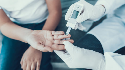 Image of a doctor taking a blood sample from a boy's finger.