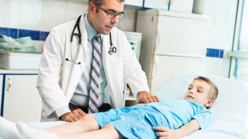 Image of little boy having tummy examination by pediatrician at doctor's office.