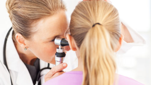 Image of a close-up of female doctor analyzing girl's ear with otoscope in hospital.