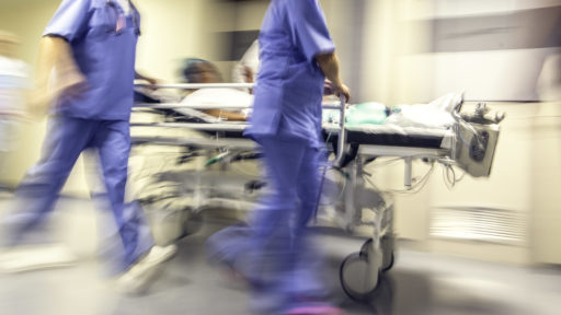 Image of doctors and nurses pulling hospital trolley.
