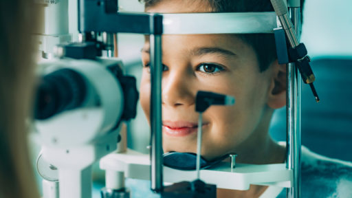 Image of an eye exam. Ophthalmologist examining boy's eyes with slit lamp