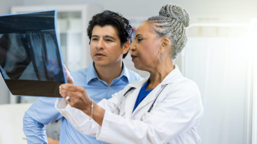 An African American doctor reviews an x-ray with an adult male.