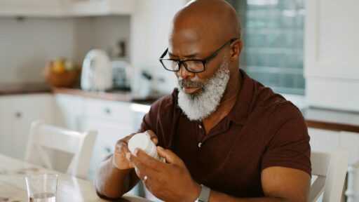 Older man with beard reading bottle label