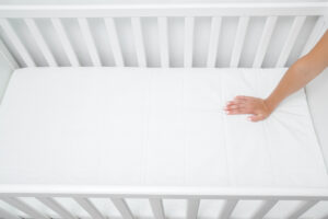 Woman testing out the hardness of a crib mattress