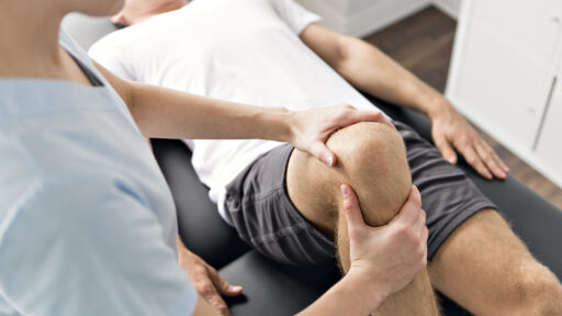an athlete working with a trainer on his knee
