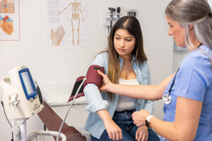 Female doctor examining a young woman patient during a medical exam in a clinic.