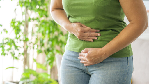 Woman touching her stomach experiencing abdominal pain at home