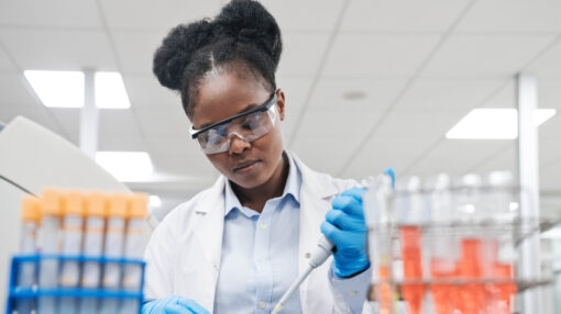 Young female scientist filling chemical through pipette while working in laboratory
