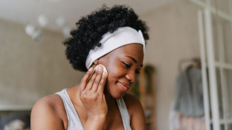 Photo of a young African American woman cleaning her skin with a tonic before going to sleep