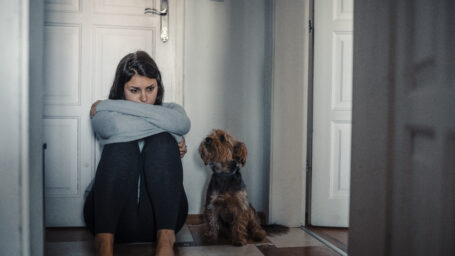 sad woman sitting on the floor with her dog.