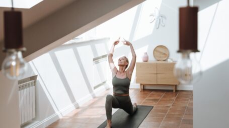 Woman doing a yoga pose on a mat in a sunlit room