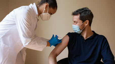 A White male receives a shot from a female medical provider