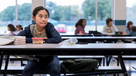 a young girl sits by herself at lunch