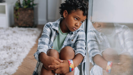 a sad boy leaning against the window.