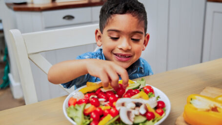 a little boy eating vegetables