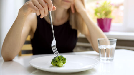 a woman eating a piece of broccoli